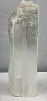 Front view of the tall natural selenite crystal mineral lamp showing translucent columnar structure and carved bottom portion.