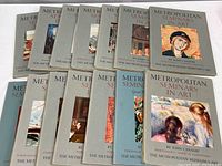 Fourteen closed portfolios from The Metropolitan Museum of Art Seminars in Art series by John Canaday arranged in two rows, grey covers with various art reproductions on front covers visible.