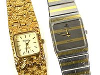 Close-up of dial faces and part of bracelets of the two watches, showing gold-tone Lucien Piccard Dupont and silver and gold Baume & Mercier watches