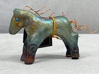 Side view of the hand-painted Raku-style clay horse figurine showing the turquoise eye and copper wire mane and tail details.