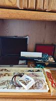 Wide view of jewelry trays, boxes, and assorted pieces on wooden surface