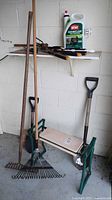Photo showing rakes, gardening bench, shovels arranged against wall beneath a shelf with weed killer and hand tools