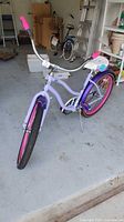 Front angle view of purple and pink Huffy bike with 24-inch wheels in garage.