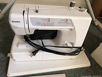 White Kenmore sewing machine model 385.12916 with pattern and length stitch controls and power cord.