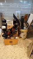 Photo showing the wooden knife block with several knives and the ceramic crock with assorted kitchen utensils on a kitchen countertop.