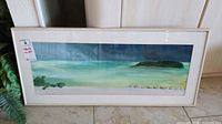 Full view of the large framed beach print in a white frame under glass.