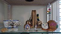 Full view of glass shelf with nautical decor items including bookends, kitty piggy bank, photo frame, coral ornament, and porcelain boat bowl.
