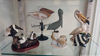 Full view of all five pelican figurines on glass shelf