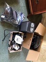 Wide view of boxed items showing antennas, cables, and sound therapy speakers inside and around cardboard boxes.