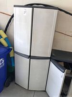 Front view of white plastic two-door garage cabinet closed with one door slightly open showing contents inside.