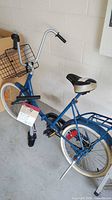 Vintage blue Schwinn bicycle with wire front basket, upright handlebar, and black and beige seat.