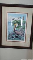 Full framed print showing pelican and three flying birds over water and branches.