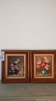 Pair of framed oil on canvas floral prints with brown and gold frames.