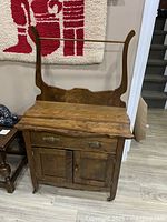 Front view of antique oak wash stand with brass handles, showing two drawers, two cabinet doors, and towel rack above.