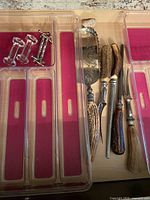 Set of carving utensils with decorative handles, crystal knife rests in plastic tray.