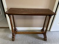 Front view of the walnut console table showing its rectangular top and turned legs.