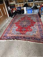 Full view of Persian rug on concrete floor showing overall pattern, color, and size.
