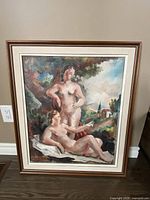 Full view of the framed oil painting showing two nude women in a landscape setting.