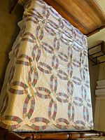 Full view of the double wedding ring quilt spread over a bed, showing floral multi-color fabric forming rings on white background with scalloped edges.