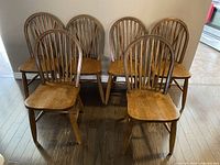 Set of six wooden braceback chairs arranged with four at back and two in front, showing classic design and brown wood finish.