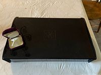 Exterior view of large black SKS branded jewelry box with accompanying velvet box containing pearl tie pin.