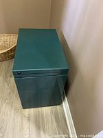 Side and top view of teal metal file cabinet showing compact size and minor surface wear.