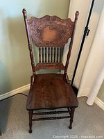 Full view of vintage oak pressback chair showing carved backrest, turned legs, and contoured seat with minor wear.