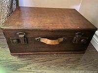 Top and front view of rectangular brown wooden storage box showing leather handles and metal latch locks.