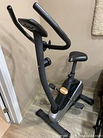 Side view of the black and silver Weslo Pursuit 2.3 U upright bike showing curved handlebars, padded adjustable seat, pedals, and stable base.