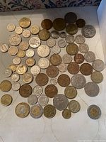 Top-down view of a large assortment of diverse world coins in copper, silver, and gold colored tones, including various sizes and designs.