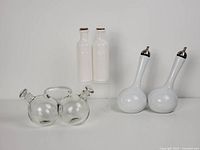 Photo showing the three oil and vinegar cruet sets: clear glass double ball set, white Toscana porcelain set, and another white porcelain set with metal tops.