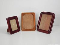 Three assorted vintage teak wood frames displayed side by side, showing front view with no pictures inside.