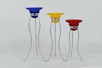 Three Intervall Memphis tealight holders by Ikea, in blue, yellow, and red glass cups on silver metal stands, arranged side by side on a white background.