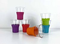 Six Bormioli Rocco Brio latte coffee cups arranged with colorful silicone sleeves stacked and lying down.