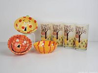 Three pumpkin-themed ceramic face bowls arranged in a group with vibrant orange, yellow, and cream colors and playful facial features, showing seasonal design and quality.