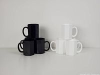 Stacked black and white octagonal mugs showing shape and colors.