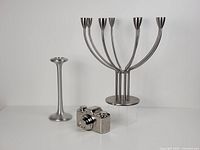 Metal candle holders and ceramic camera figurine arranged side-by-side on a white surface