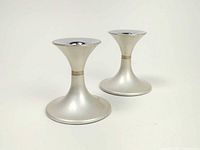 Pair of silver-tone Emalox candlestick holders photographed against a white background. Shows base and tapering top design with minor wear.