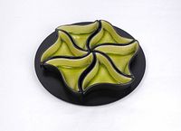 Top-down photo showing all four green ceramic serving plates arranged in a circular formation on the black round ceramic tray.