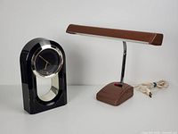 Both items side by side on a surface: the black and gold Regency style quartz clock and the brown Silvine desk lamp with chrome neck and cord.