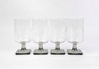 Front view of 4 identical vintage glass goblets with cylindrical bowls and square pedestal bases in smoke grey color.