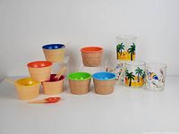 Seven vintage ice cream cups and four retro plastic summer cups arranged showing colors and designs