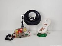 All three telephones displayed side by side: transparent phone, black donut phone, baseball SportFone.