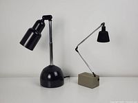 Front view of both lamps on a white surface against a gray background, showing size and design differences.