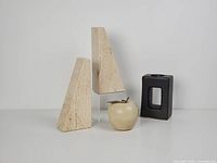 Set showing both travertine bookends, ceramic apple with brass stem, and black ceramic tealight holder.
