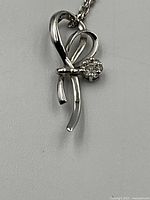 Close-up of pendant showing ribbon-like design and round diamond setting