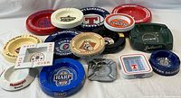 Front view of all 16 ashtrays showing various beer brand logos and colors