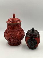 Front view of both cinnabar lacquer carved lidded jars, showing detail and scale.