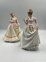 Two Royal Doulton figurines displayed side by side showing front and side angles. "Gift of Love" on left in cream and pink dress; "Yours Forever" in white with pink trim on right.