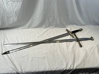 Two full-length swords crossed on white backdrop.